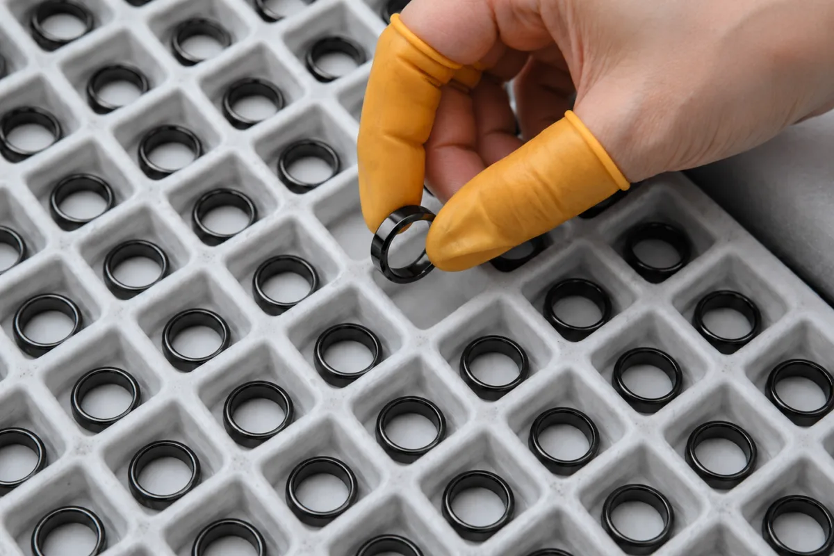 Black PVD stainless steel rings inspected in a factory tray for batch quality control